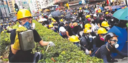  ?? (Tyrone Siu/Reuters) ?? A PROTESTER holds a pan to use as a cover from tear gas during a protest in Hong Kong’s Sham Shui Po district yesterday.