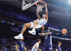  ?? Chris Szagola / Associated Press ?? North Carolina’s Armando Bacot, left, hangs on the rim after a dunk past St. Peter’s Clarence Rupert during the first half Sunday.