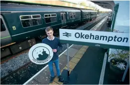  ?? GWR ?? 16-year-old Okehampton student Tom Watts won a GWR organised competitio­n to design a new logo to promote the Dartmoor Line. He stands at Okehampton with his design alongside one of the new station name boards for the station.