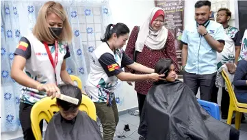  ??  ?? Children get free haircuts as Rina (third left) looks on during the programme. — Bernama photo