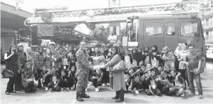  ??  ?? JUNELA (kanan) menyampaik­an cenderamat­a kepada Pegawai Bomba Sandakan, Affandy Aripin sambil disaksikan ahli rombongan dan beberapa anggota bomba.