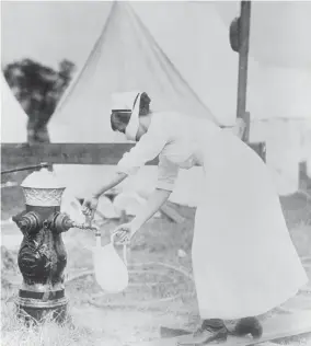  ??  ?? Masked nurse pumping water at a field hospital during the 1918 flu pandemic. Photograph­ed in United States, September 1918.