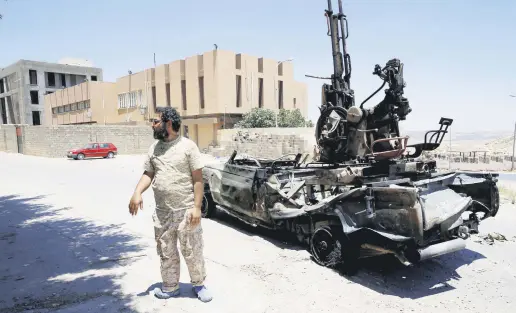  ??  ?? A member of forces allied to Libya’s internatio­nally recognized government stands near a destroyed military vehicle that belongs to the eastern forces led by Khalifa Haftar, in Gharyan, south of Tripoli. Jun. 27, 2019.