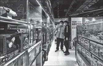  ?? BLOOMBERG ?? Visitors stand in front of product displays during the opening of Miniso Group Holding Ltd’s Top Toy flagship store in Shanghai.