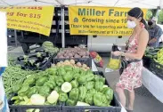  ?? Cliff Grassmick, Daily Camera file ?? Chrissy Savinell fills up her bag at the Miller Farms stand in August at the Boulder County Farmers Markets. It will do year- round curbside pickup.