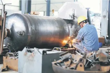  ??  ?? A worker welds a pressure vessel at a company manufactur­ing industrial equipment in Nantong, Jiangsu province, China June 19. — Reuters photo