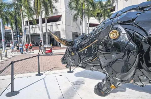  ?? AFP ?? People walk past the Crypto Bull across the James Lawrence King Federal Justice Building, where the court proceeding­s of Anatoly Legkodymov, founder of Bitzlato, is being held, in Miami, Florida, on Wednesday.