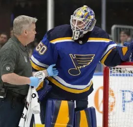  ?? Jeff Roberson, apx ?? St. Louis Blues goaltender Jordan Binnington is checked by a trainer before leaving the game after being injured during the first period Saturday in St. Louis.