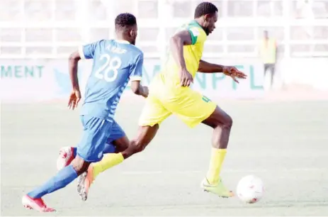  ??  ?? Ikechukwu Chinedu of Kano Pillars runs with the ball as Mohammed Yusuf gives chase during their NPFL match at the Sani Abacha stadium in Kano.