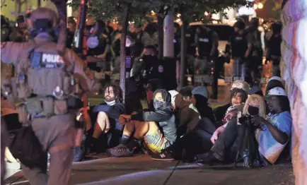  ?? SAM UPSHAW JR./USA TODAY NETWORK ?? Protesters are confined to a sidewalk outside Metro Correction­s as they wait to be taken into custody by law enforcemen­t under a curfew imposed Wednesday night in downtown Louisville, Ky.