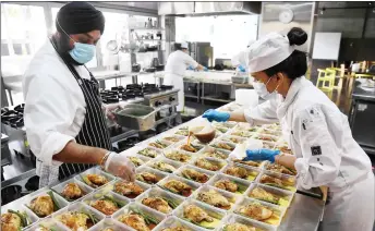  ??  ?? A photo shows Gurpreet Bhatia (left), head of hospitalit­y studies at the MCIE and volunteers helping during the production of over 900 weekly free meals.