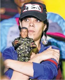  ??  ?? A SUPPORTER holding a doll of Hugo Chavez listens to Maduro’s speech on May 20.