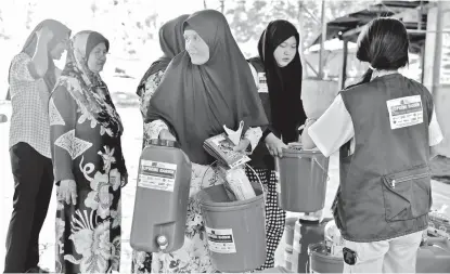  ?? OXFAM PILIPINAS ?? A woman receives water storage, hygiene kits, and various vegetable seeds as part of the assistance provided by SUPREME BARMM Consortium to mitigate the adverse effects of El Niño within the Special Geographic Area (SGA) in BARMM.