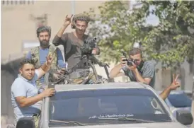  ?? LEFTERIS PITARAKIS/AP ?? Turkish-backed Syrian opposition fighters cheer from a car as they drive around the border town of Akcakale, Sanliurfa province, southeaste­rn Turkey, on their way to Tal Abyad, Syria, Monday.