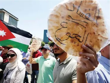  ??  ?? محتجون أردنيون يرفعون رغيف خبز ويرددون هتافات ضد الضريبة أمام مكاتب النقابة العمالية في عمان أمس. ( رويترز)
