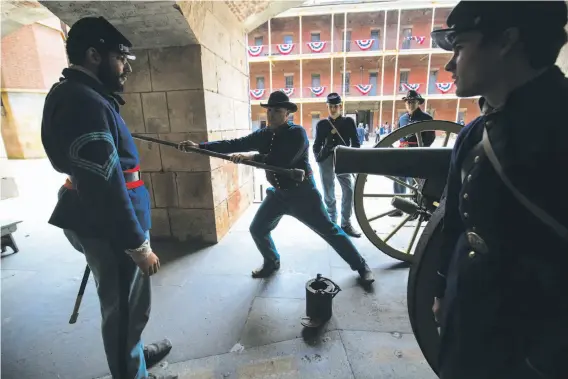  ?? Photos by Paul Kuroda / Special to The Chronicle ?? Re-enactors dressed in Union blue uniforms demonstrat­e how to fire a cannon during Civil War Living History Day at Fort Point in San Francisco.