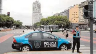  ??  ?? Arriba, la Avenida 9 de Junio de Buenos Aires. Sobre estas líneas, un grupo de activistas emula a los personajes de «El cuento de la criada»