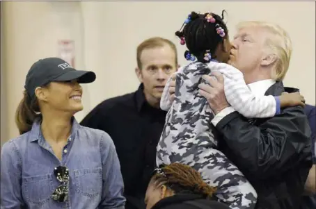  ?? SUSAN WALSH — THE ASSOCIATED PRESS ?? President Donald Trump and Melania Trump meet people Saturday affected by Tropical Storm Harvey during a visit to the NRG Center in Houston. Here he lifts this girl into his arms to give her a kiss. It was his second trip to Texas in a week.