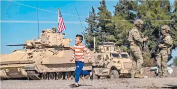  ?? — AFP ?? Children play as US soldier patrol in Syria’s northeaste­rn Hasakah province.