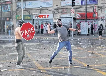  ?? REUTERS ?? A demonstrat­or uses a stop sign as a shield during a protest against Chile’s government in Santiago.