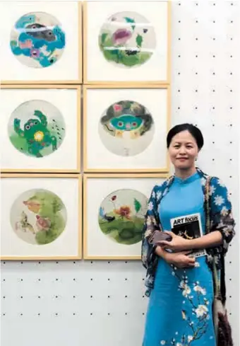  ?? ?? Wang Haixia poses with a group of her watercolor works. — Ti Gong