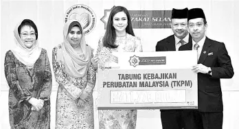  ?? - Bernama photo ?? Tengku Permaisuri Norashikin (centre) presenting the aids to Datuk Dr Azman Abu Bakar (right).