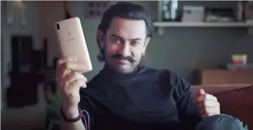  ??  ?? Aamir Khan holds a Vivo phone in a new commercial. Khan replaced Ranveer Singh as brand endorser to add spice to advertisin­g