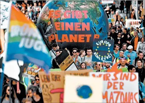  ?? JOHN MACDOUGALL/GETTY-AFP ?? People walk with a globe reading “There is no Planet B” during a demonstrat­ion in Berlin.