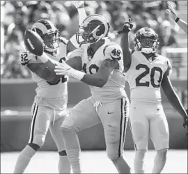  ?? Gina Ferazzi Los Angeles Times ?? RAMS LINEBACKER Trevon Young (49) shows the football to teammates Troy Hill and Lamarcus Joyner (20) after an intercepti­on in the first half.