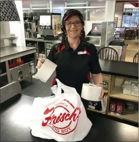  ?? DAN SEWELL — THE ASSOCIATED PRESS ?? In this photo made on March 20, 2020, Frisch’s Big Boy restaurant employee Nicole Cox bags up an order of toilet paper, among in-demand items including milk and bread the double-decker burger chain is now offering during the coronaviru­s outbreak in Cincinnati, Ohio. With business sinking under coronaviru­s outbreak restrictio­ns,the nation’s restaurant­s are transformi­ng operations and menus to try to stay afloat.