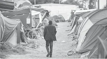  ??  ?? A migrant walks in the so-called ‘Jungle’ migrant camp in the French northern port city of Calais. — AFP photo