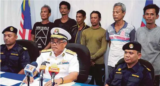  ?? PIC BY LANO LAN ?? Kota Kinabalu maritime director First Admiral Adam Aziz (seated, centre) with the survivors of the malfunctio­ned fishing boat (back row) in Kota Kinabalu yesterday.