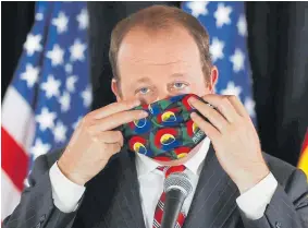  ?? David Zalubowski, The Associated Press ?? Gov. Jared Polis puts on his face mask to make a point during a news conference May 6 to update reporters on the state’s efforts to stem the rise of the new coronaviru­s.