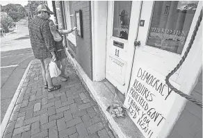  ?? DANIEL LIN/AP ?? Passersby examine the menu at the Red Hen restaurant Saturday in Lexington, Va. The owner asked the White House press secretary to leave.