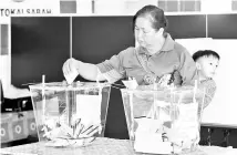  ??  ?? A woman with her child casting her votes at Dewan Pekan Nabalu in Tuaran. - Bernama photo