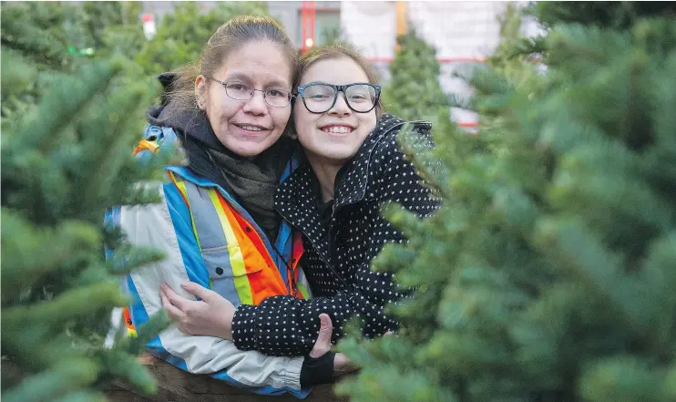  ?? GERRY KAHRMANN/PNG ?? Marcia Tait and daughter Makani volunteer at Aunt Leah’s Christmas tree lot. The charity helps former foster children and mothers at risk of losing custody.