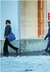  ??  ?? Personas pasan por delante de un escaparate que anuncia las rebajas en medio de la nieve