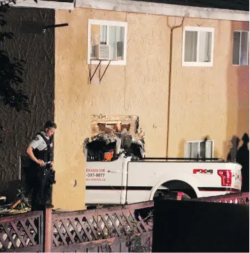 ?? SHANE MACKICHAN / POSTMEDIA NEWS ?? A pickup truck crashed through a fence and into the back of a Surrey home Wednesday night, narrowly missing a sleeping four-month-old baby, who was rescued after initially being trapped under the truck.