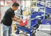  ??  ?? This photograph taken on Dec 5, 2016 shows a worker placing inbound parcels on a conveyor belt for coding at the sorting section of
the Singapore Post (SingPost) ecommerce logistics centre in Singapore.(AFP)