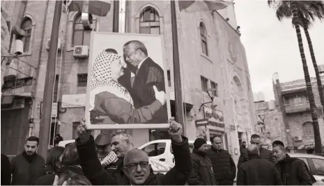  ?? AFP ?? A Palestinia­n man holds a portrait of Yasser Arafat and Nelson Mandela outside the municipali­ty building in Bethlehem on Friday