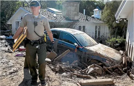  ?? PHOTO: WASHINGTON POST ?? Santa Barbara County police officer Dennis Thomas leads Dina Landi through the home where she was staying when a mudslide struck.