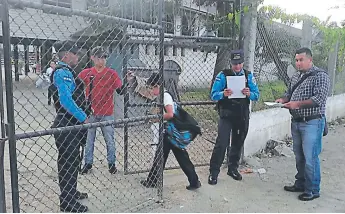  ??  ?? PLEITO. Dos agentes de la Policía Nacional evitan que el maestro Migdonio Edelin Hernández ingrese a la escuela Esteban Guardiola. Un sector de los padres de familia lo apoya por denunciar.