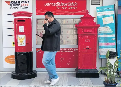  ?? CHANAT KATANYU ?? A man walks past red postboxes outside the Thailand Post branch at Government House. The booming e-commerce market has spurred greater demand for the state enterprise’s express parcel service, despite continued issues with mishandled packages.