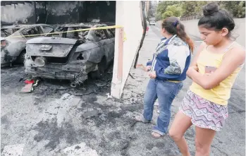  ??  ?? Rubenia Blanco y su hija Yesenia observan los daños que provocó un incendio en su edificio de apartament­os en Duarte. /FOTOS: AURELIA VENTURA