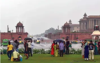  ?? — PTI ?? Tourists enjoy rainfall at Vijay Chowk in New Delhi on Sunday. Rains in some parts of the city provided much-needed relief to the people from the sultry weather. The city received 1.8 mm rain on Sunday morning, said a MeT department official.