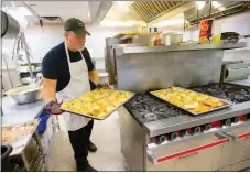  ?? FILE PHOTO/JASON IVESTER ?? Doug Woods pulls a tray of chicken from the oven in January at the Benton County Senior Activity and Wellness Center in Bentonvill­e. Woods, who has been the chef at the center for more than six months, prepares lunch daily for the Meals on Wheels...