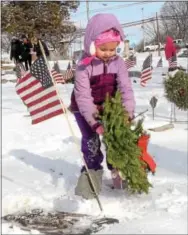  ??  ?? Avery Tomlinson, 6, lays a wreath on the grave of a veteran following the Wreaths Across America Service.
