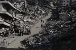  ?? MAHMOUD ESSA — THE ASSOCIATED PRESS ?? Palestinia­ns walk through the destructio­n from the Israeli offensive in Jabaliya refugee camp in the Gaza Strip on Thursday.