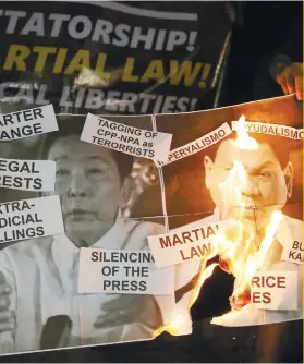  ?? AP FOTO ?? RIGHTS WATCH: Protesters burn pictures of the late dictator Ferdinand Marcos and President Rodrigo Duterte in a rally on Jan. 26, 2018 in Manila.