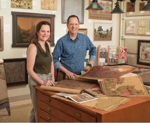  ??  ?? left Bolling & Co. partners Gwen Jones and Bo Sullivan examine vintage sample books in the studio located in Jones’ garage. top Running the length of the house, the warm living room is comfortabl­e with vintage family furnishing­s. The architectu­ral bookcases were added.